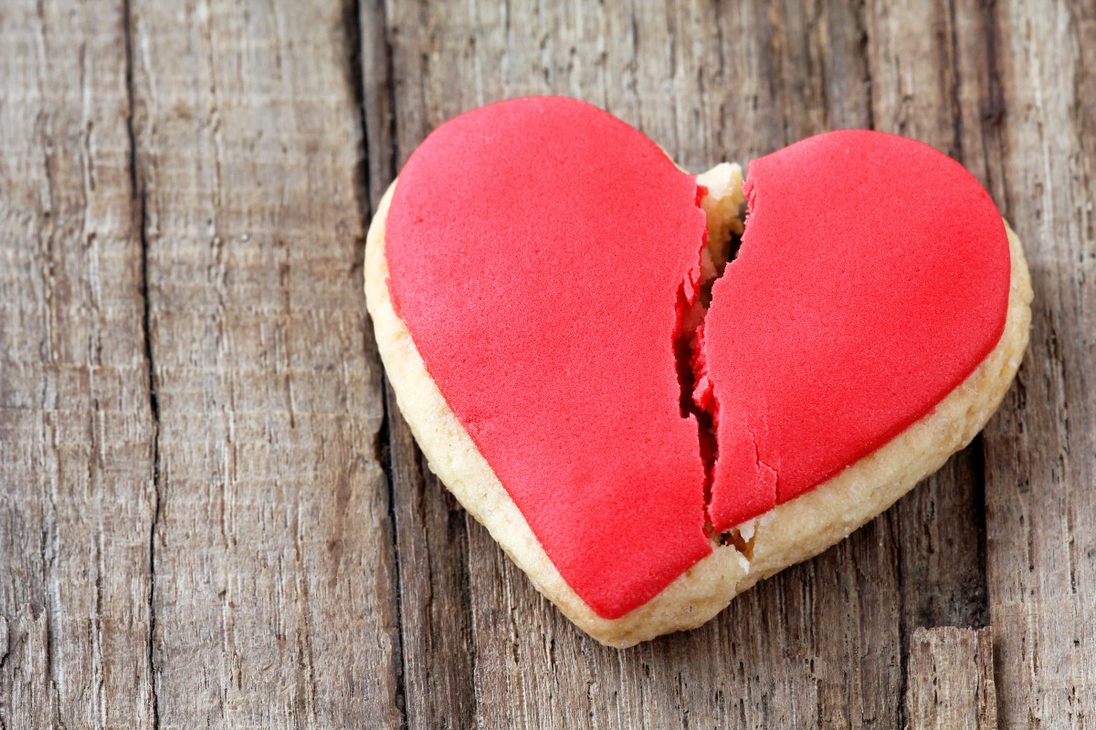 Cracked heart shaped cookie decorated with red icing as a concept of broken heart, breakup and end of relationship