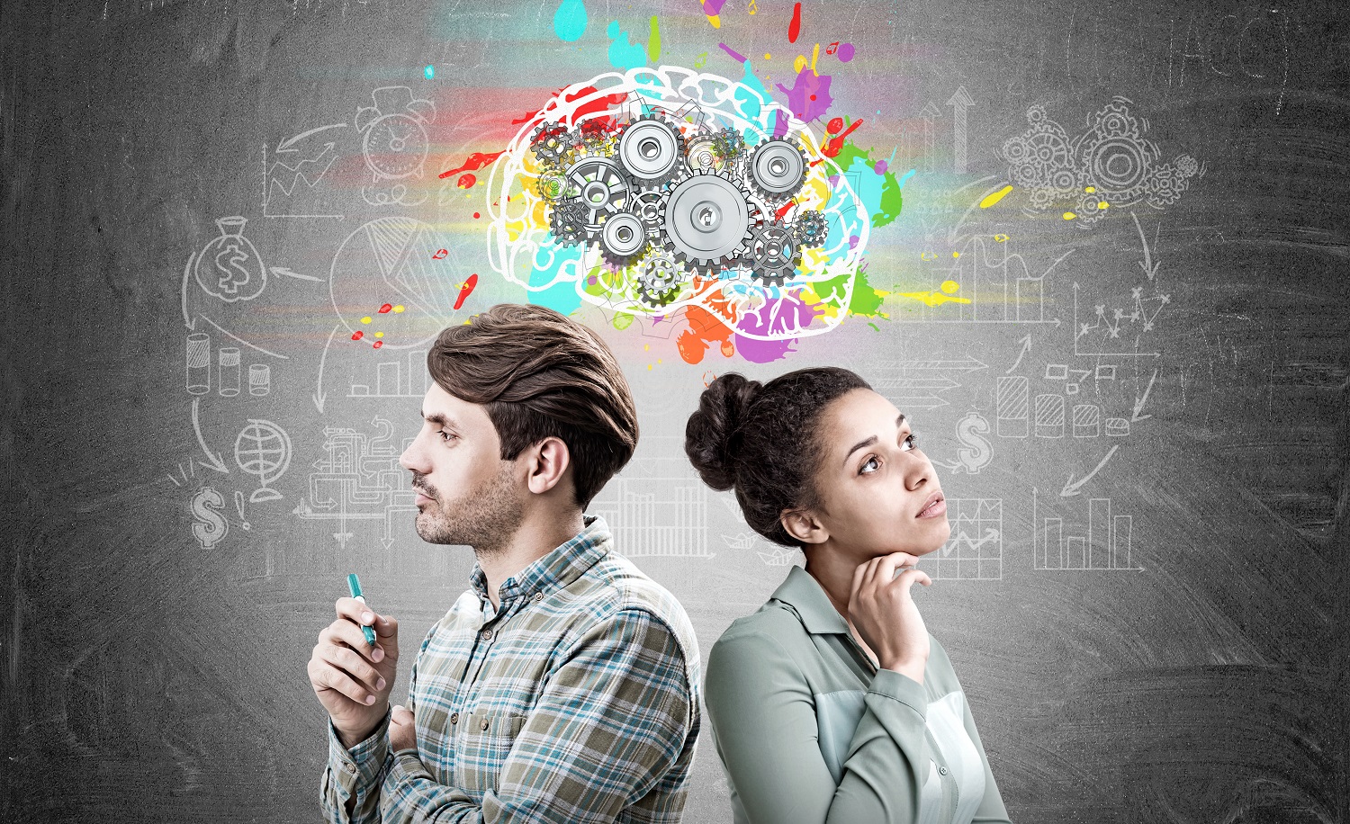Portrait of a man and an African American woman standing back to back near a blackboard with a colorful brains sketch and cogs on it.