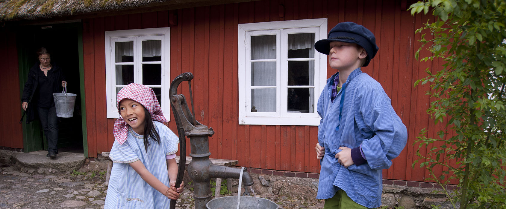 Hjälp till i Skånegården Barn pumpar vatten vid Skånegården, Skansen