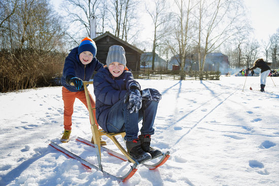 Sportlov på Skansen Sportlov på Skansen. Ett barn på spark, ett annat barn puttar på.