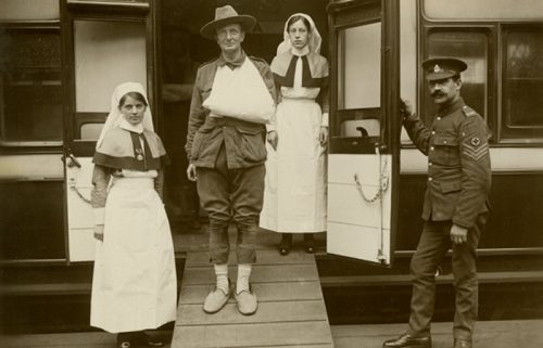 A solider alighting from a carriage pictures with two nurses and an officer