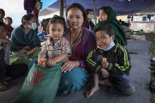 Krizal, 3, ja Binaya, 5, odottavat äitinsä Laxmin kanssa teltta-asutuksessa Bhaktapurissa, Nepalissa. Perhe sai hätäapua Pelastakaa Lapsilta. Pakkaus sisältää lämpimiä vaatteita, hattuja, peittoja sekä hygieniatarvikkeita. Kuva: Jonathan Hyams/Pelastakaa Lapset