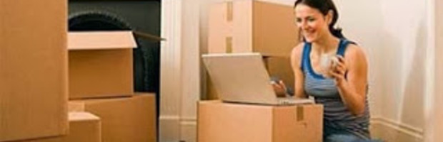 Girl in room with laptop and boxes in floor