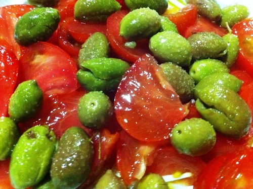 Ensalada de buenos tomates de la tierra y olivas partías.