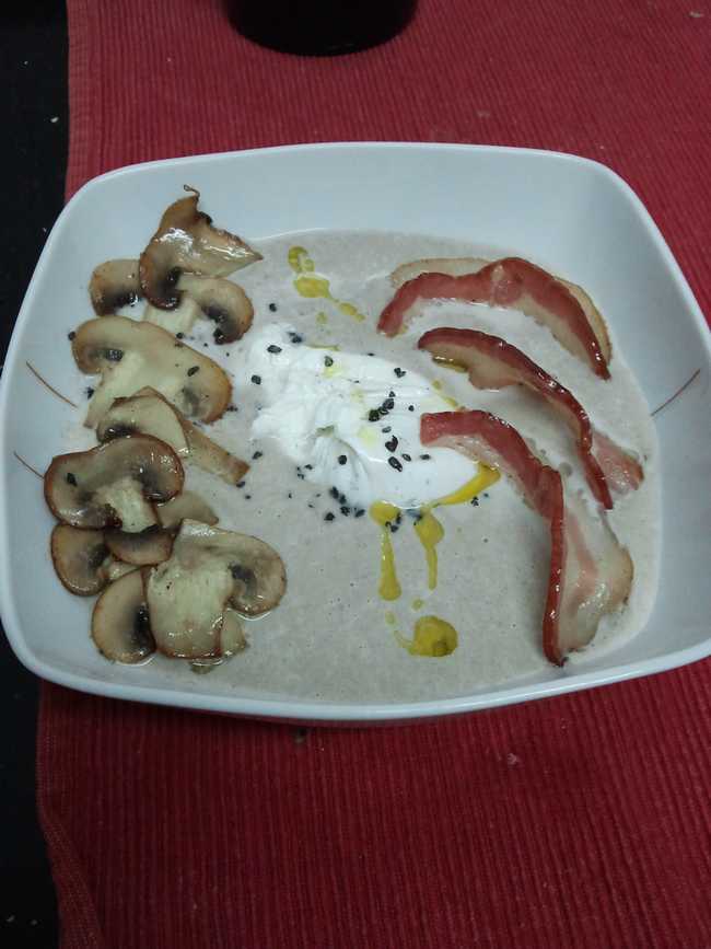Crema de champiñones con huevo poché y tiras de bacon.