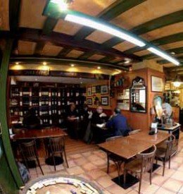 La taverna d'en Pep en Barcelona Comedor de la entrada, con la estantería de vinos al fondo.