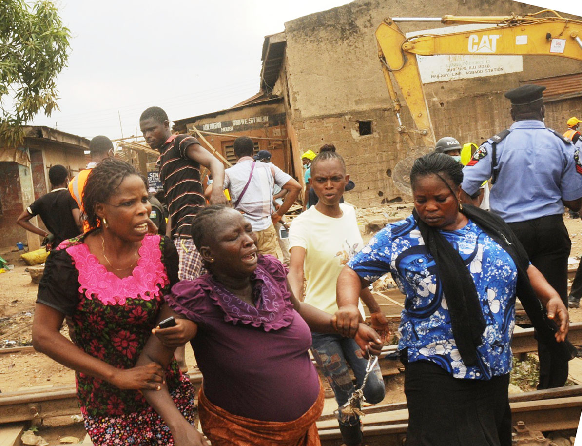 Pregnant woman being assisted out during the demolition of houses