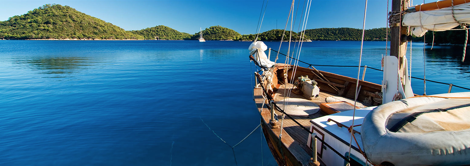 Sailboat anchored in deep blue sea in front of the Pakleni islands in Hvar (Croatia)