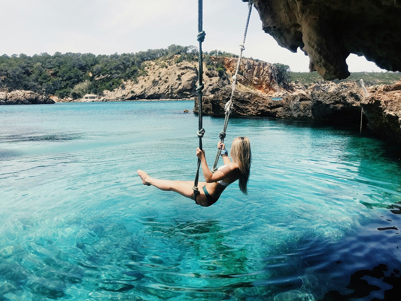 Cala Xarraca swing over turquoise waters, Ibiza