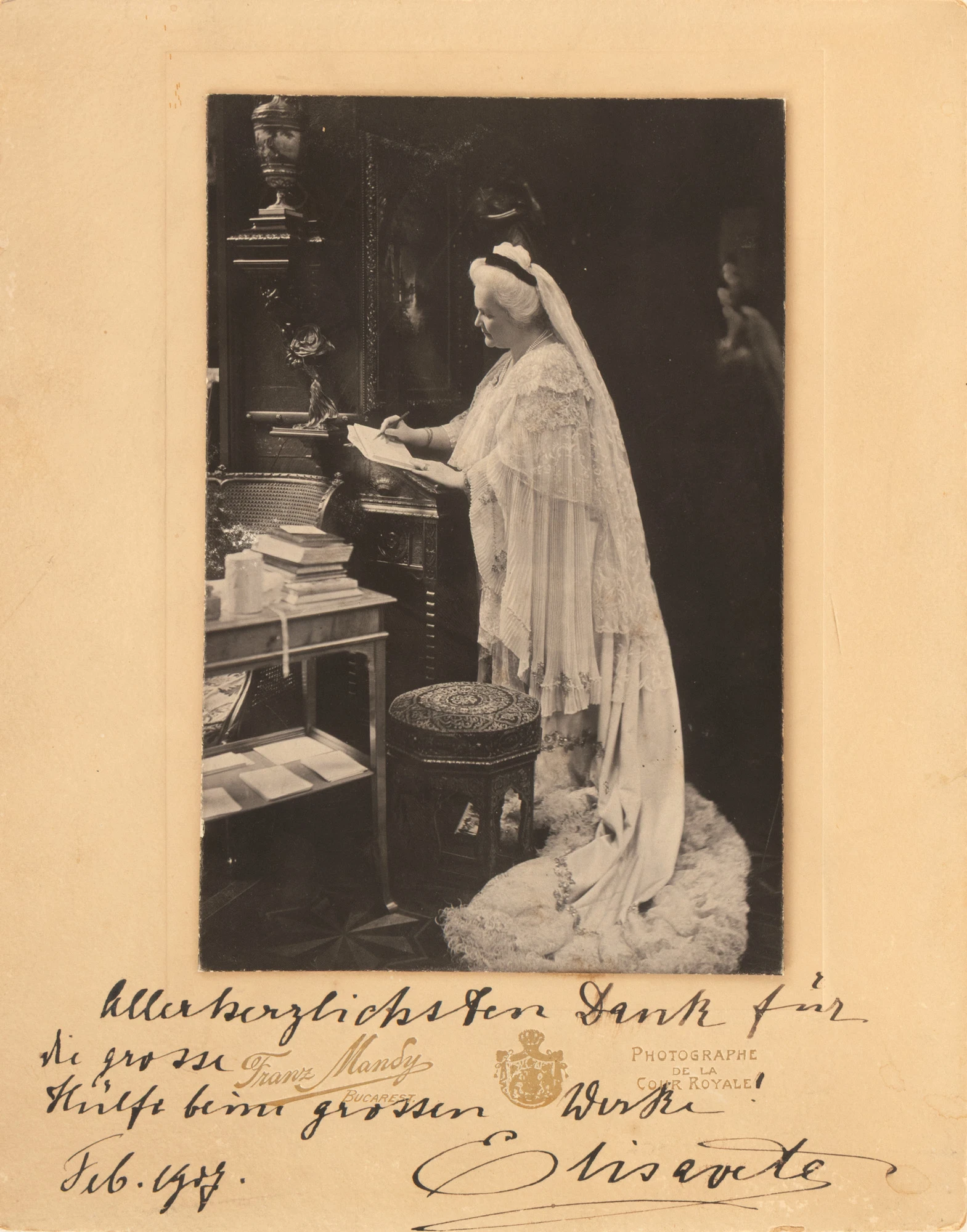 Fotografie ilustrând-o pe Regina Elisabeta în cabinetul de lucru, scriind, atelier fotografic Franz Mandy, București, 1907, cu dedicația și semnătura olografe ale Reginei