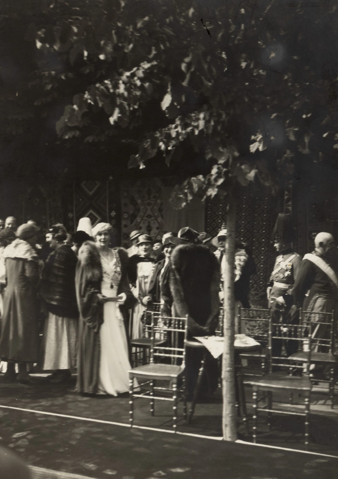 Fotografie de presă ilustrând-o pe Regina Maria la Castelul Peleș, înconjurată de doamnele de la curte, clișeu fotografic al agenției Trampus, Paris, cca. 1930