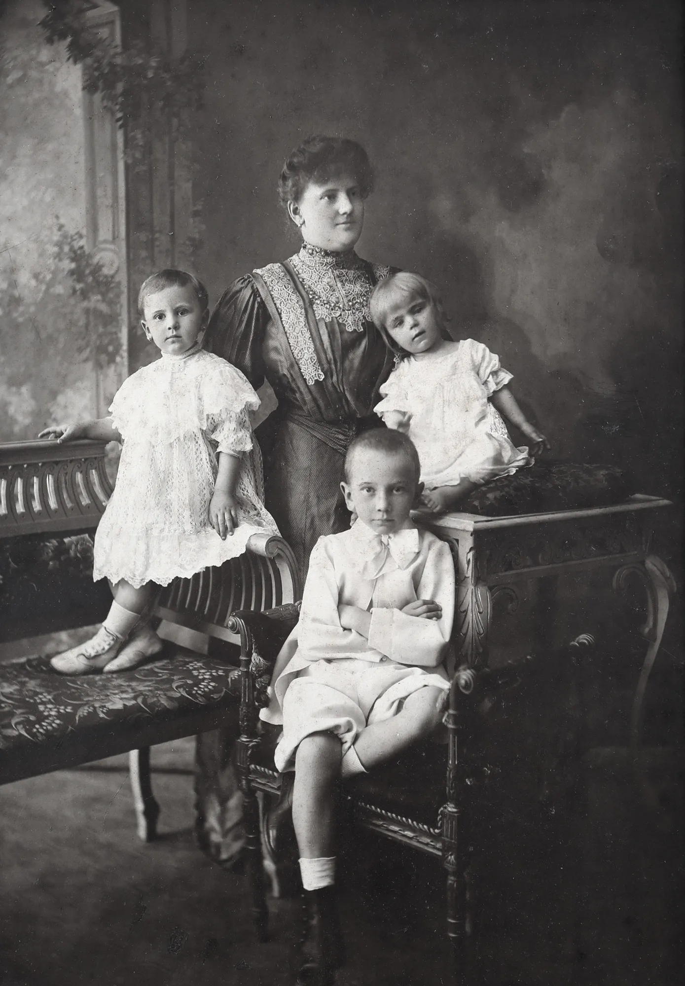 Melancholic typical family photograph from the end of the century, a mother with her three children, circa 1900
