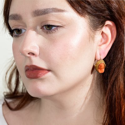 Pereche de cercei din aur și coral, reliefând profiluri feminine, însoțită de cutia originală