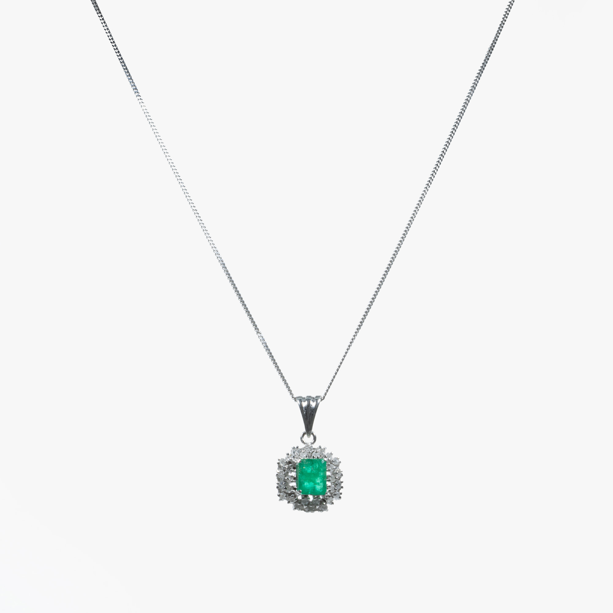 White gold and platinum chain with pendant, centrally decorated with emerald, surrounded by diamonds