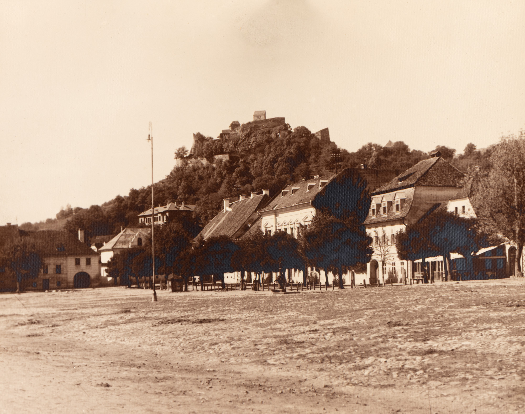 Fotografie ilustrând o panoramă cu cetatea Rupea și case tradiționale, atelier Kohler, Rupea, perioada interbelică