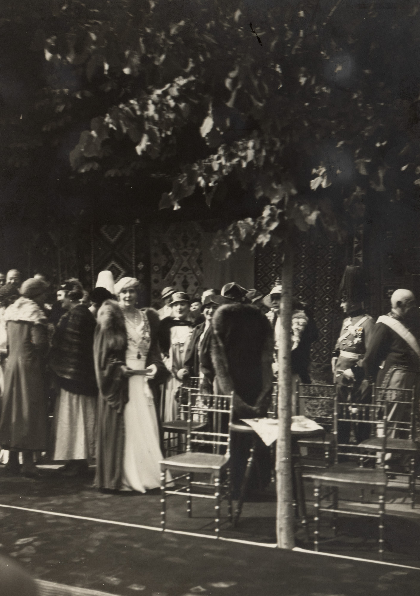 Fotografie de presă ilustrând-o pe Regina Maria la Castelul Peleș, înconjurată de doamnele de la curte, clișeu fotografic al agenției Trampus, Paris, cca. 1930