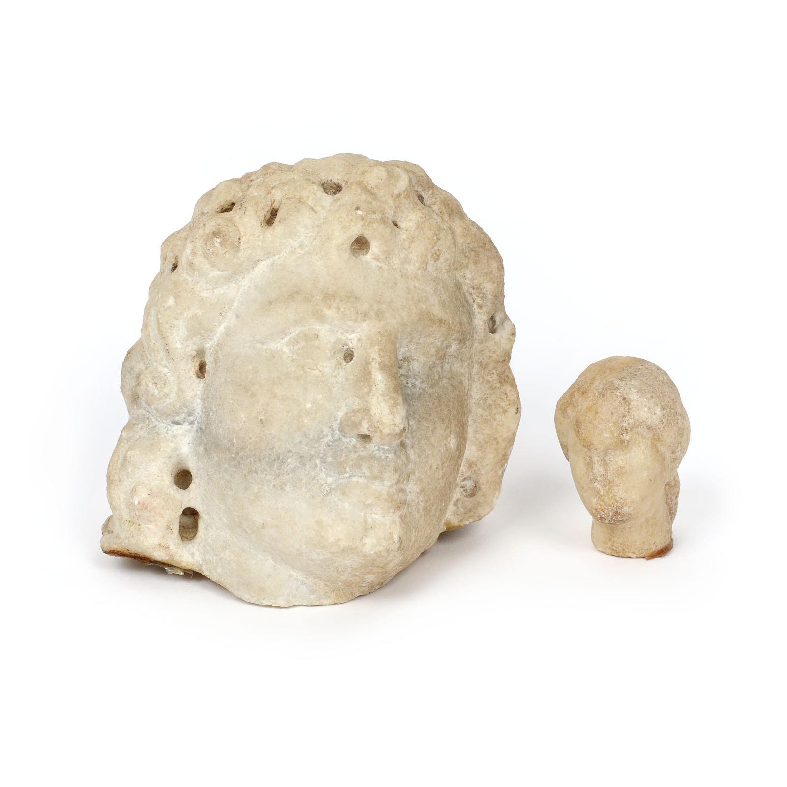 Lot format din două fragmente de statuete de marmură, ilustrând un cap de Helios și un cap de femeie, sec. III î.e.n. - III e.n., provine din colecția dr. Horia Slobozianu