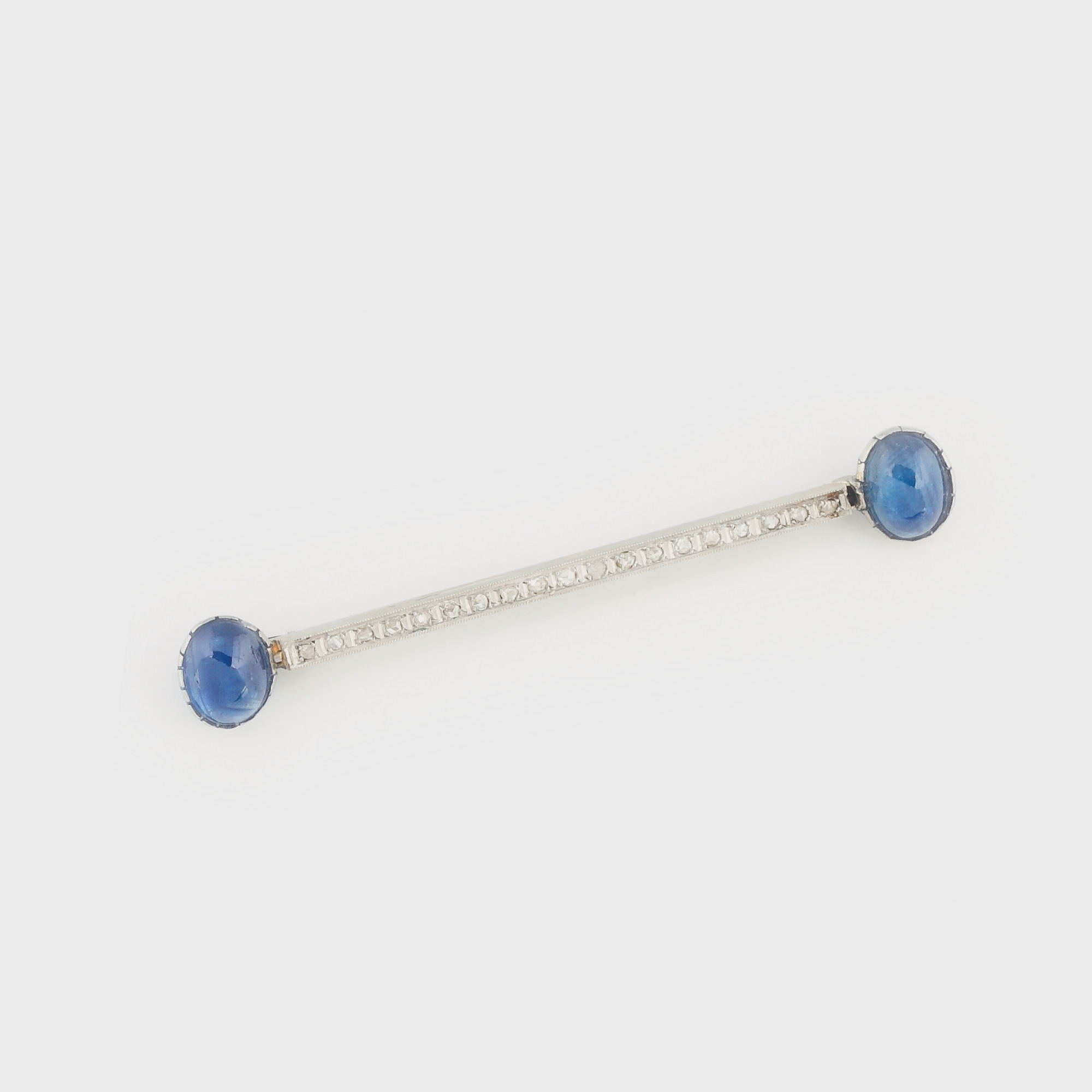 Broşă din platină, decorată cu suită de diamante încadrată de 2 safire caboşon, cca. 1920