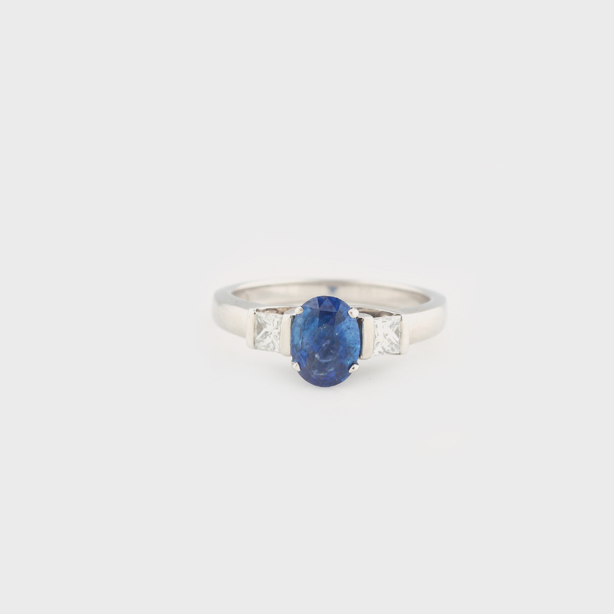 Inel din aur alb, decorat cu safir oval încadrat de două diamante 