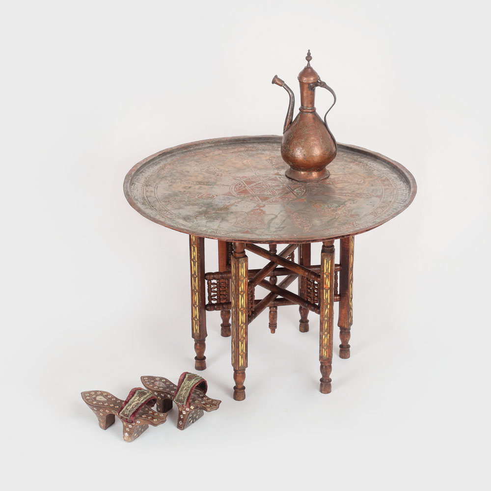 Interior oriental: papuci de hamam, decorați cu sidef și intarsii de argint, ibric din aramă și măsuță otomană, decorată cu sidef