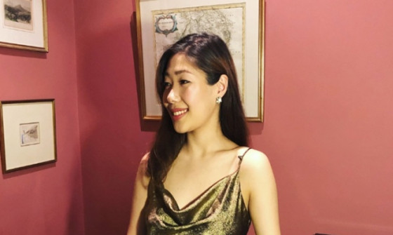 Nurry Lee stands elegantly wearing a sleek olive dress