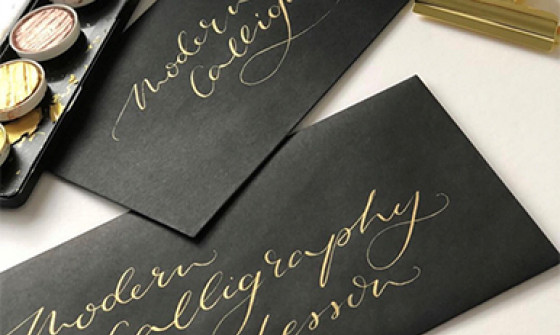 Two black envelopes lay on a table with gold calligraphy writing on them