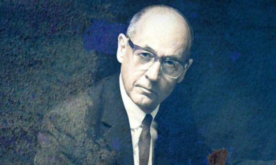 Andy Fairweather Low sits in a suit with his guitar on his lap in a grainy black and white photograph