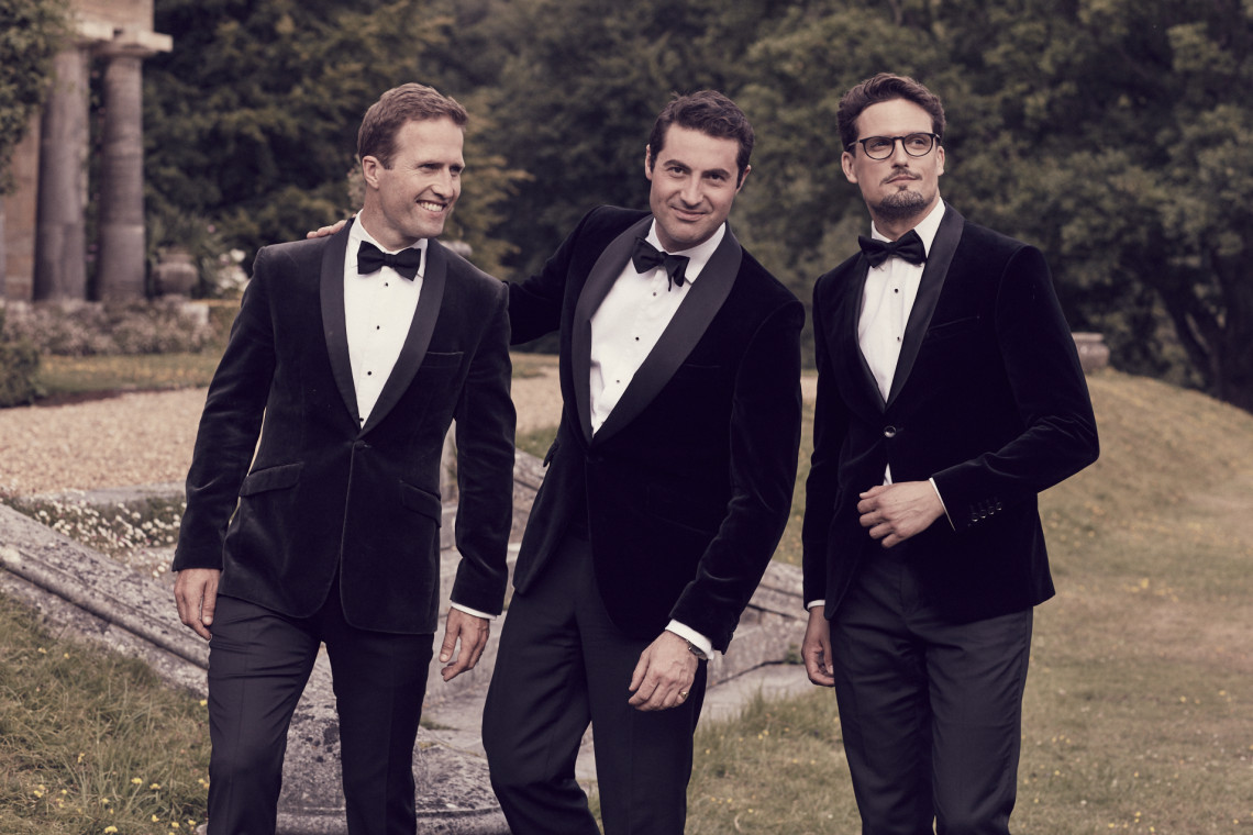The members of Blake stand in tuxedos on a lawn