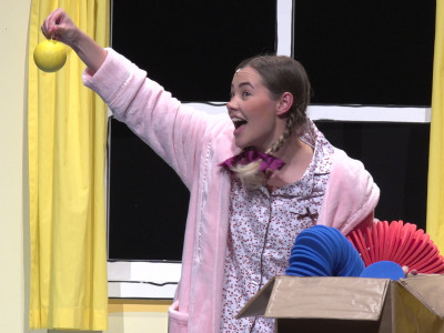 A girl holds up a bauble as she pulls it from a box of decorations