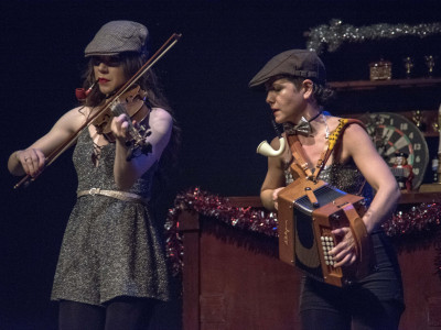 A woman plays the accordion next to a violinist