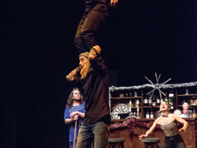 A man stands on the shoulder of another performer