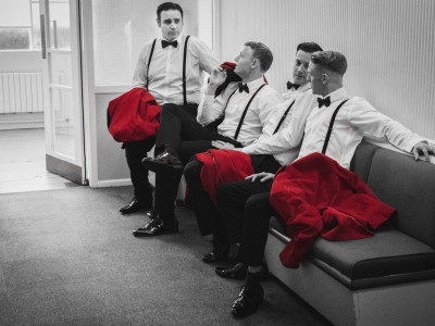 Bye Bye Baby sit on a sofa. The image is in black and white with just their suit jackets in red.