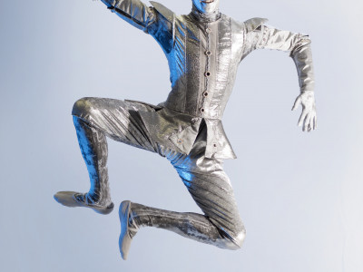 Tinman is jumping in the air. He is wearing a silver costume