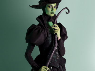 A full body shot of the Wicked Queen holding her staff. She is wearing a black dress, her skin is green