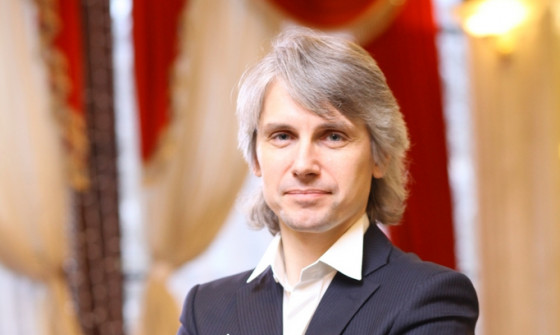 Dmitry Vasiliev is standing with his arms crossed. He is holding a baton in his hand