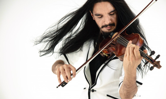Nemanja Radulovic is wearing a white blazer. He is playing the violin.