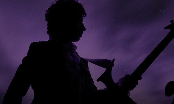 Prince stands in silhouette in front of a purple background