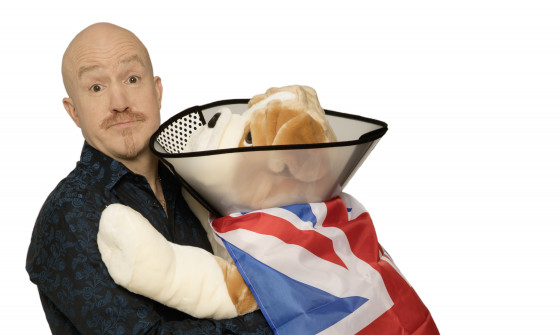 Andy Parsons is standing holding a stuffed Bulldog. The dog is wearing a Union Jack