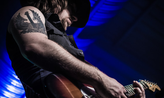 A close up of 'Bon Jovi' from below. His face is shaded and the focus is on his guitar.