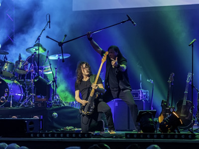 A guitarist kneels at the front of the stage playing.