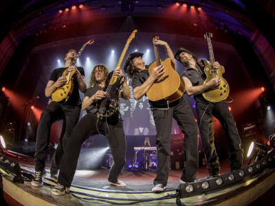 Four guitarists perform on stage. Taken through a fisheye lens