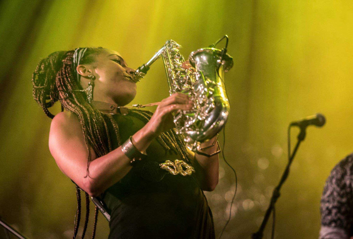 A woman plays the saxophone in yellow lighting