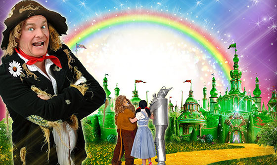 The Lion, the Scarecrow, Dorothy and the Tinman all stand on the yellow bring road facing a rainbow above the Emerald City.