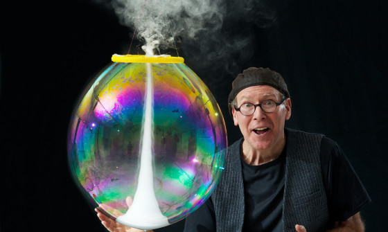 Louis Pearl holds a large, colourful bubble with smoke coming out of it.