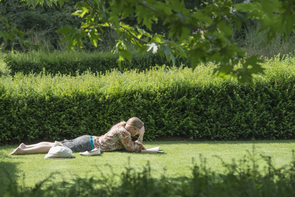 Lady lying on the grass reading a book in the summer.