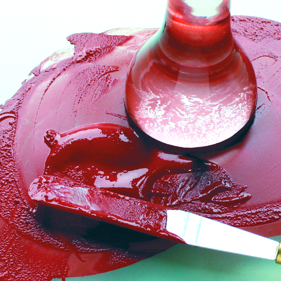 Glass pestle and metal palette knife grinding plant material to make red organic paint.