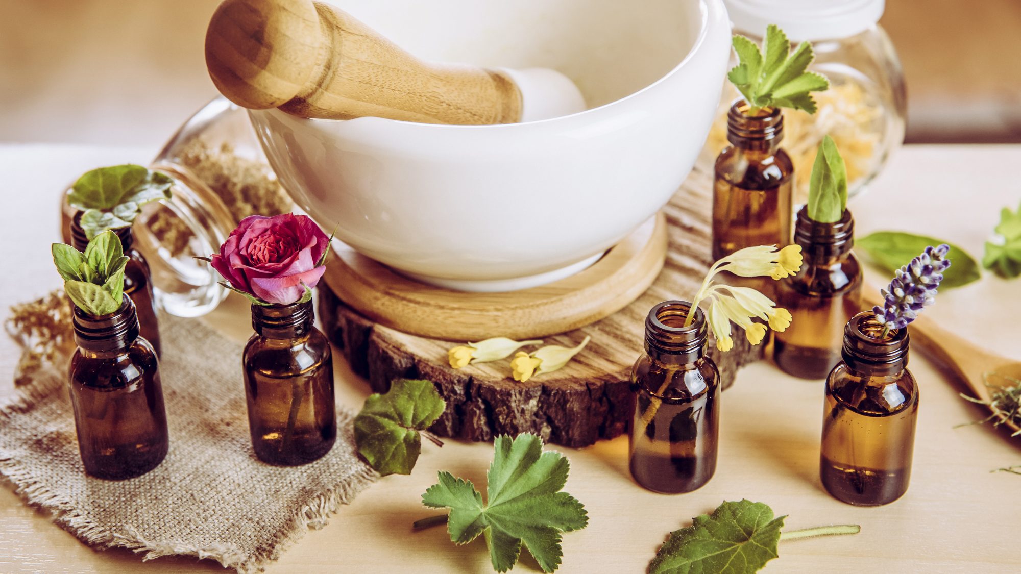 a pestle and mortar with plant material and small brown bottles