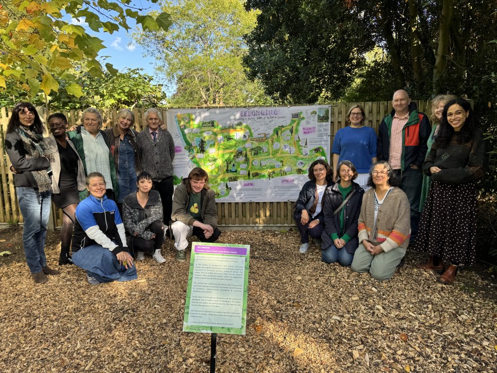 A group of people pose either side of a map of Cambridge University Botanic Garden.