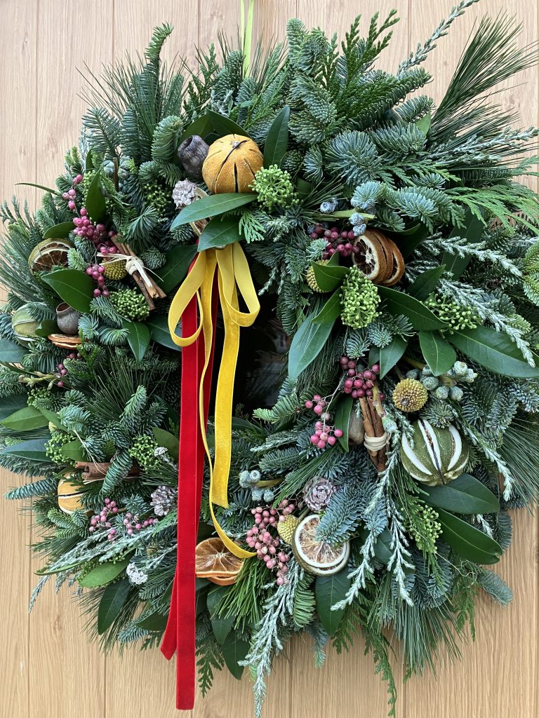 a festive wreath made from spruce, dried fruit, mixed foliage and berries