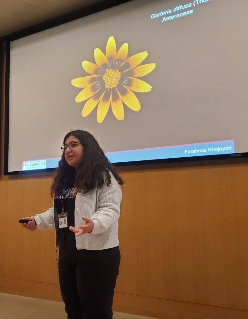 A woman stands in front of a screen to give a presentation at the University of Cambridge.